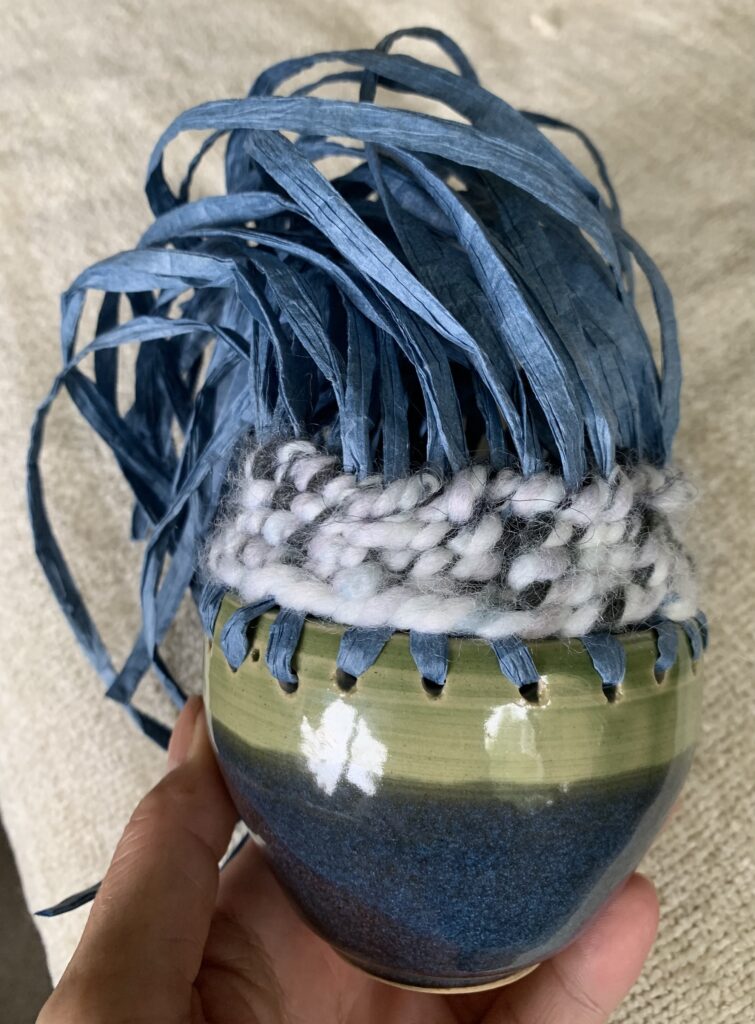 Same pot but with 5 layers of chunky grey yarn woven between the blue warp uprights